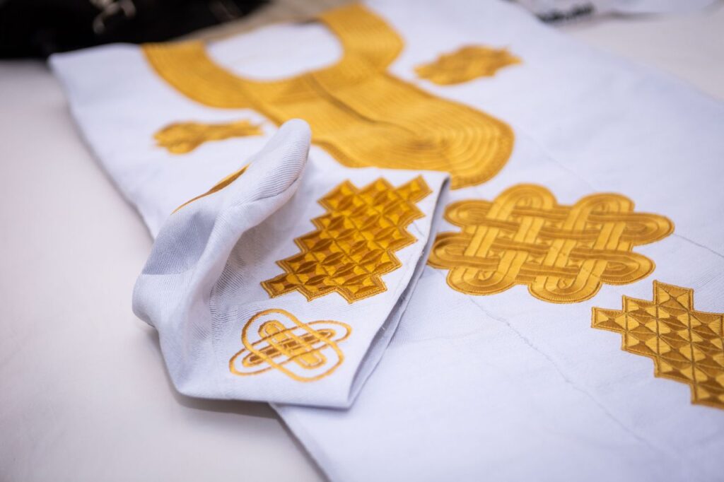 Close-up of intricately embroidered traditional African garment with golden patterns.