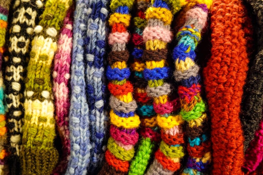 A vibrant collection of handmade knitted wool textures in various colors.