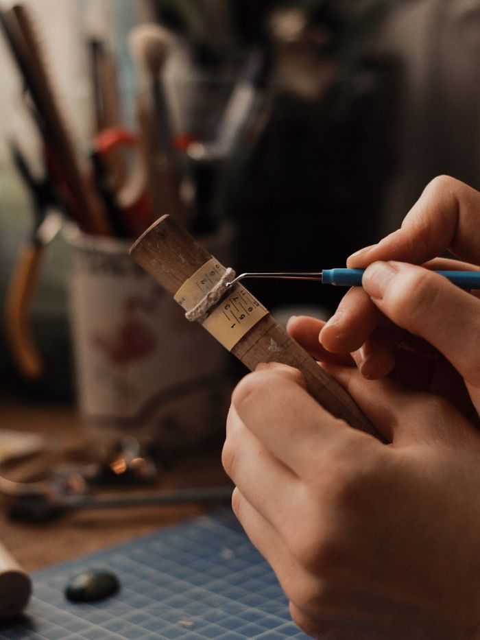 Artisan jeweler carefully crafting a silver ring with precision tools, showcasing skill and craftsmanship.